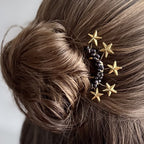 Goldener Sternen-Haarschmuck in einem eleganten Dutt, goldene Sterne und dunkle Perlen detailreich im Haar platziert.