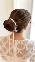 Festlicher Haarschmuck mit weißen Perlen und Blumen, seitlich am Dutt getragen, passend zur Kommunionfrisur.