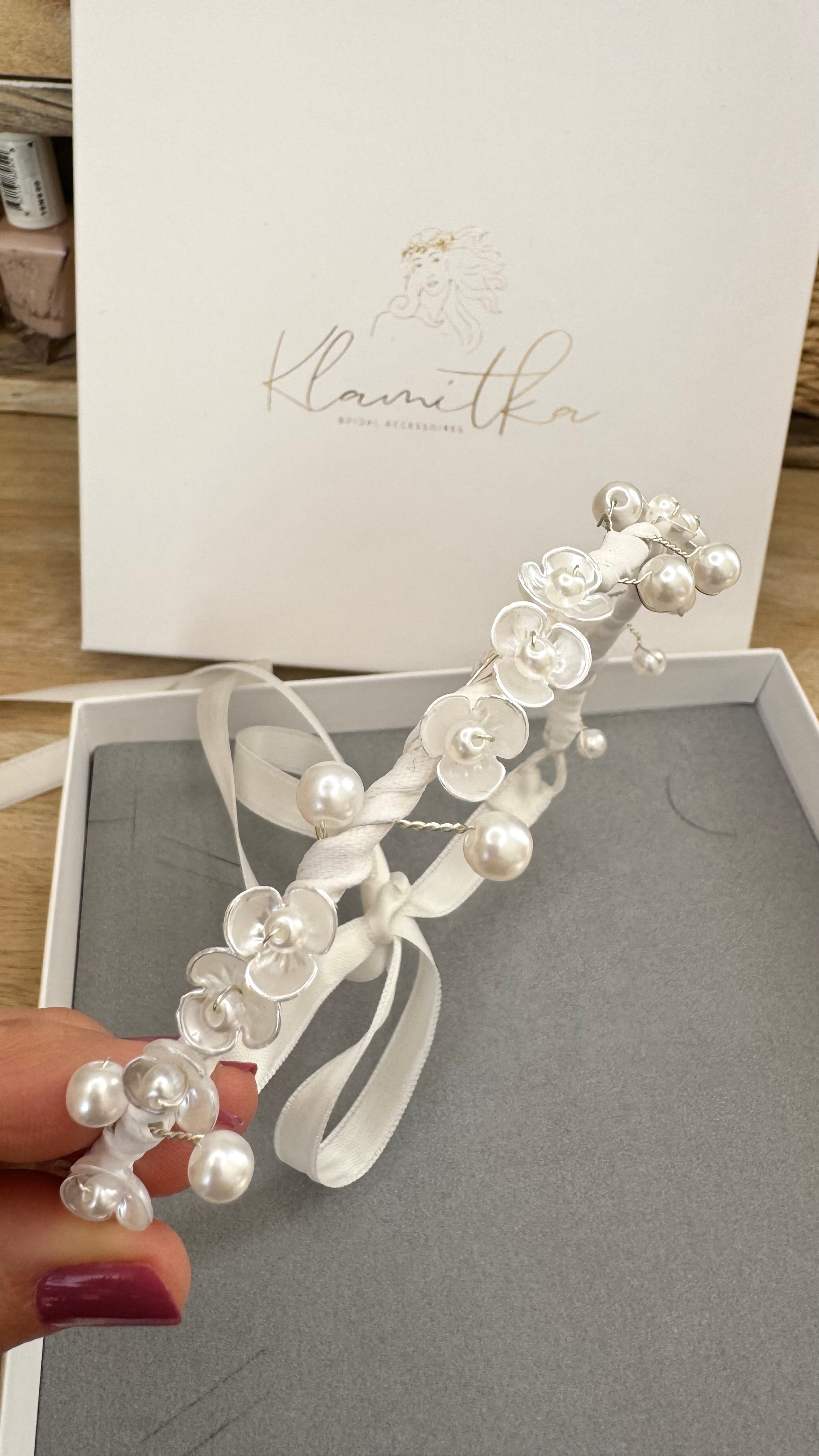 Feine weiße Blumen und runde Perlen auf flexiblem Haarschmuck, ideal für Duttfrisuren zur Kommunion.