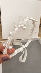 Nahaufnahme eines Kommunion-Duttbands mit satinartigen Bändern, feinen Perlen und kleinen Blütendetails, handgefertigt.