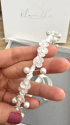 Handgefertigter Kommunion-Haarkranz mit zarten weißen Blüten und runden Perlen, Nahaufnahme der feinen Verarbeitung.