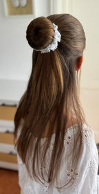 Halboffene Frisur mit Dutt und dem weißen Haarschmuck aus Spitze und Perlen. Die restlichen Haare fallen glatt über den Rücken.