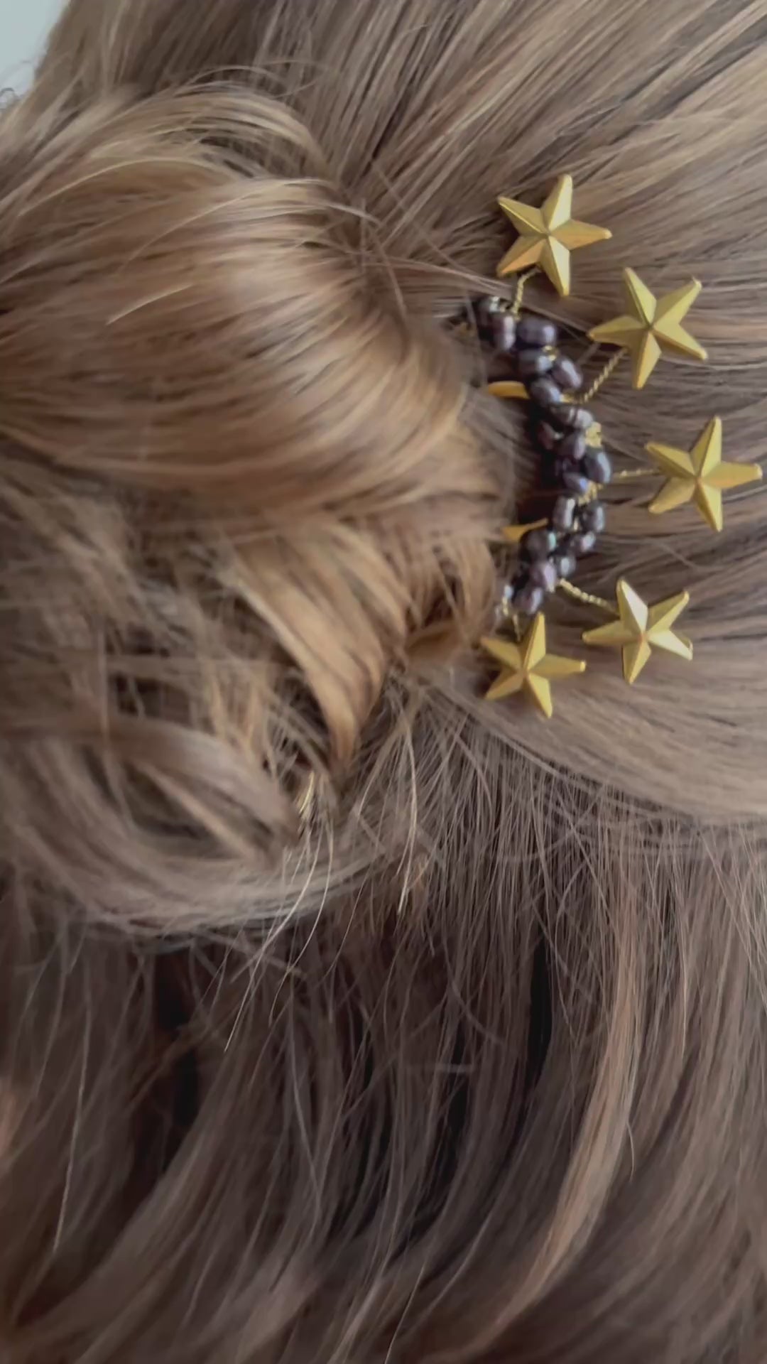Boho-Hochsteckfrisur mit lockerem Dutt und goldenen Sternen, dekoriert mit perlenbesetztem Haarkamm.